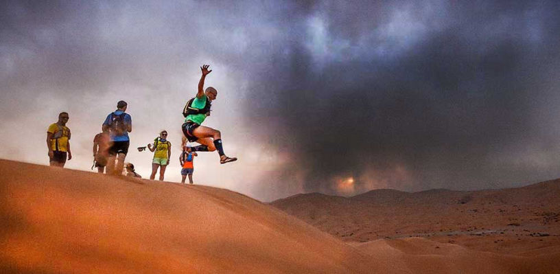 Adventure runner jumping over the dunes of the Sahara desert.
